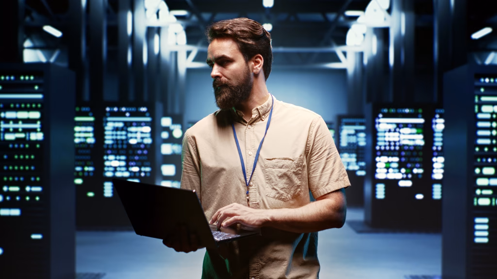 administrador de sistemas con computador monitoreando servidores